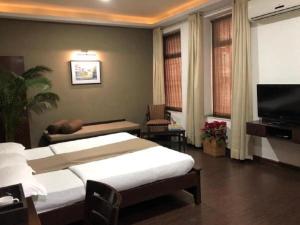 a bedroom with two beds and a flat screen tv at Hotel Ketan in Pune