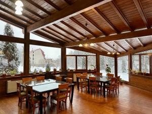 a dining room with tables and chairs and windows at Pensiunea Rasnoava in Predeal