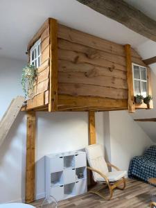 a loft bed in a room with a chair at Charmant studio sous combles in Aubigny-sur-Nère