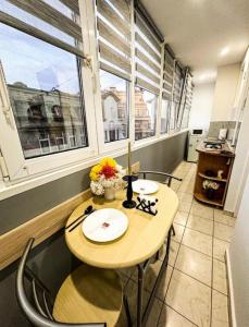 a table and chairs in a room with two windows at Welcoming Central Studio with self check in in Bucharest