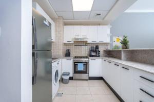 a kitchen with white cabinets and a refrigerator at WOW! 1 Bed & Sofa Bed! 10-min walk to Dubai Mall in Dubai