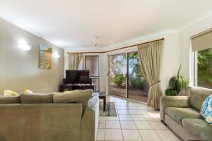 a living room with a couch and a tv at Mai at Coral Horizons: A Relaxed Beach Retreat in Palm Cove