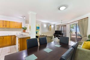 a living room with a dining table and a kitchen at Mai at Coral Horizons: A Relaxed Beach Retreat in Palm Cove