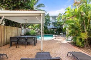 a patio with a table and chairs and a pool at Mai at Coral Horizons: A Relaxed Beach Retreat in Palm Cove