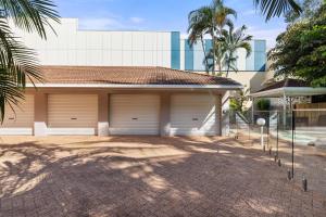 a house with two garage doors in a driveway at Mai at Coral Horizons: A Relaxed Beach Retreat in Palm Cove