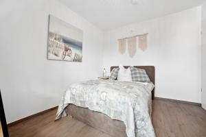 a white bedroom with a bed and a picture on the wall at Gästehaus Mönchswald 