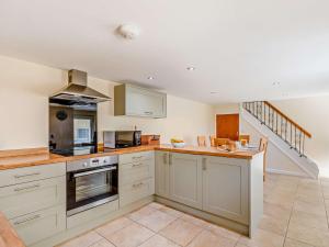 a large kitchen with white cabinets and a staircase at 3 Bed in Langtree 58822 in Langtree