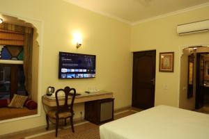 a bedroom with a desk and a tv on the wall at Heritage Resort Bikaner in Bikaner
