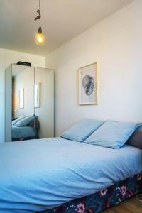 een slaapkamer met een blauw bed en een spiegel bij Grand Appartement 4 Pièces à 10min Paris (80m2) in Vitry-sur-Seine