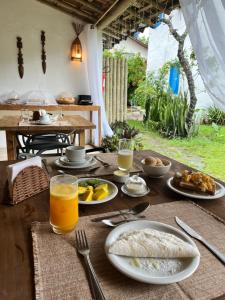 uma mesa de madeira com pratos de comida e sumo de laranja em Casa Roure Pousada em Trancoso