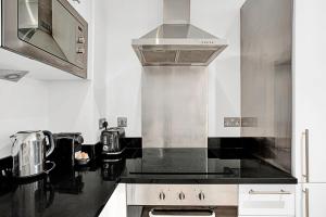 a kitchen with a stove and a microwave at Urban Retreat Stylish 1-Bed Bliss in London