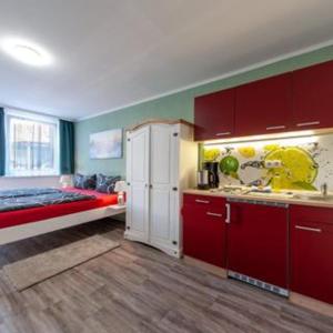 a kitchen with red cabinets and a white refrigerator at Großer Gartenbungalow Nr 3 mit Terrasse - Strandvogtei Sellin in Ostseebad Sellin
