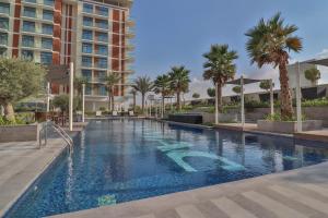 una piscina con palmeras y un edificio en Elegant Studio at Damac Celestia, Dubai south - Ezytrac vacation Homes, en Dubái