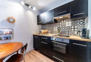 a kitchen with black cabinets and a wooden table at Appartement Charmant à Lille in Lille