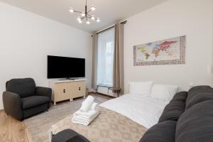 Vistula River 2-Bedroom Apartment في كراكوف: غرفة معيشة مع أريكة وتلفزيون وكرسي
