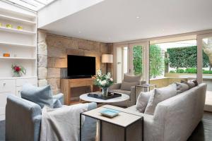 a living room with two couches and a tv at Elegant Paddington Sandstone Cottage with Parking in Sydney