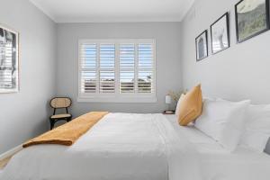 een witte slaapkamer met een groot bed en een raam bij Ocean's Embrace - A Local's Haven at Bondi Beach in Sydney