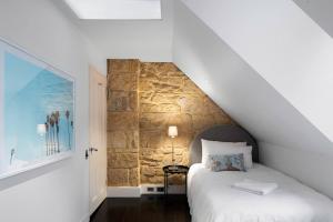 1 dormitorio con cama y pared de piedra en Elegant Paddington Sandstone Cottage with Parking en Sídney