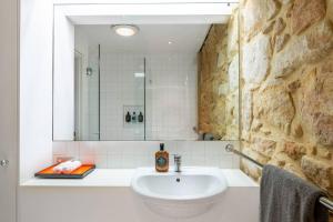 a bathroom with a sink and a stone wall at Elegant Paddington Sandstone Cottage with Parking in Sydney