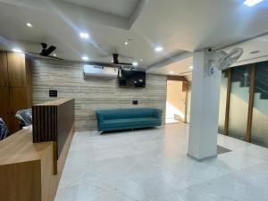 a lobby with a blue couch and a television at Hotel Royal Elite in Rajkot