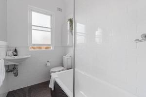 een witte badkamer met een toilet en een wastafel bij Ocean's Embrace - A Local's Haven at Bondi Beach in Sydney