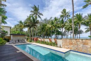 einen Pool in einer Villa mit Palmen in der Unterkunft Rojo at Island Views—A Breezy Beachfront Retreat in Palm Cove