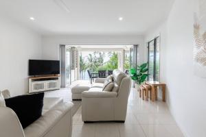 ein Wohnzimmer mit 2 weißen Sofas und einem TV in der Unterkunft Rojo at Island Views—A Breezy Beachfront Retreat in Palm Cove