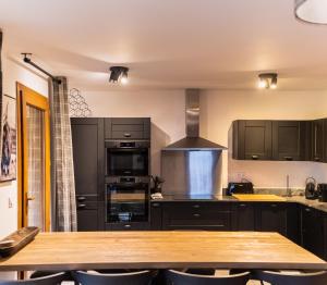 a kitchen with black cabinets and a wooden table at Alpine Creek Chalet Luxury Ski-in in Morzine