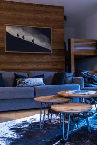 a living room with a blue couch and two tables at Alpine Creek Chalet Luxury Ski-in in Morzine