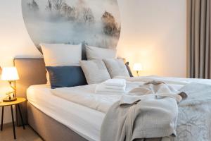 um quarto com uma cama com lençóis brancos e almofadas em Residenz - Nebelgruß - Seeterrasse - Sauna - Parkplatz em Bad Zwischenahn