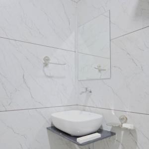 een witte badkamer met een wastafel en een spiegel bij Hotel Royal Elite in Rajkot