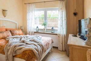 een slaapkamer met een bed, een raam en een televisie bij Altes Strandhus Casa Stranddune in Scharbeutz