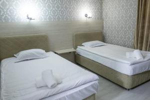 2 camas en una habitación de hotel con sábanas blancas en Алматы Транзит №1, en Turksib