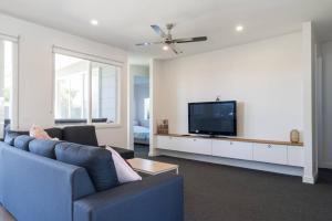 a living room with a blue couch and a flat screen tv at The Rose Among the Buds in Rosebud