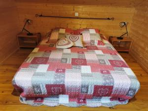 Una cama con edredón en una habitación en La Rose des Vents, en Les Vastres