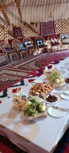 une table avec des assiettes de nourriture au-dessus dans l'établissement KARAKALPAK ETNO VILLAGE, à Noukous