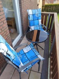 eine Terrasse mit 2 Stühlen und einem Tisch mit Kisten in der Unterkunft Ferienwohnung Gebert in Neuharlingersiel