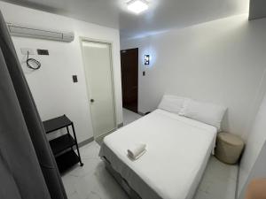 タグビラランにあるSHOWMECAS Alley Stayの小さなベッドルーム(白いベッド1台、ドア付)