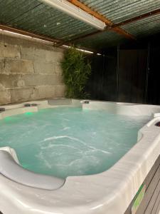 a jacuzzi tub with blue water in it at Charmante & Paisible Villa Platon - Jacuzzi & Jardin - Brive in Brive-la-Gaillarde