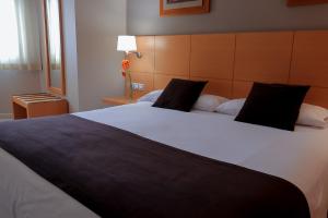 1 dormitorio con 1 cama blanca grande con almohadas negras en La City Estación, en Alicante
