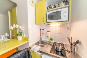 una pequeña cocina con fregadero y microondas en Montempô Apparthôtel Evry en Courcouronnes