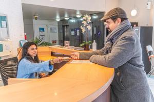 Un homme et une femme debout au comptoir dans l'établissement Montempô Apparthôtel Evry, à Courcouronnes