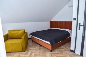 a bedroom with a bed and a yellow chair at Noclegi Beskidzkie Stodoły in Odrzechowa