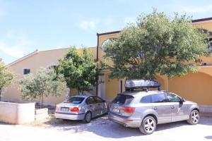twee auto's geparkeerd op een parkeerplaats voor een gebouw bij Apartments Silvana in Rogoznica