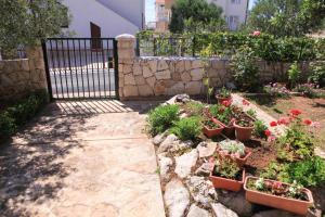 een tuin met potplanten en bloemen naast een hek bij Apartments Silvana in Rogoznica