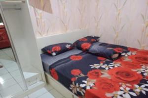 a bedroom with a bed with red flowers on it at OYO 93645 Akasia Budget in Bekasi