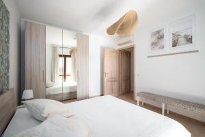 a white bedroom with a bed and a mirror at Villaggio Perlacea - Your House in Sardinia in Golfo Aranci +68 photos