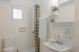 Baño blanco con aseo y lavamanos en Evianna Studios en Mousata
