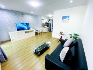 a living room with a black couch and a kitchen at Townhome in Town in Ban Ba Ngan