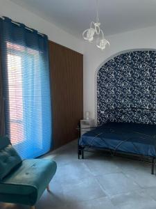 a bedroom with a bed and a chair and a window at Villa Aura in Torre del Greco